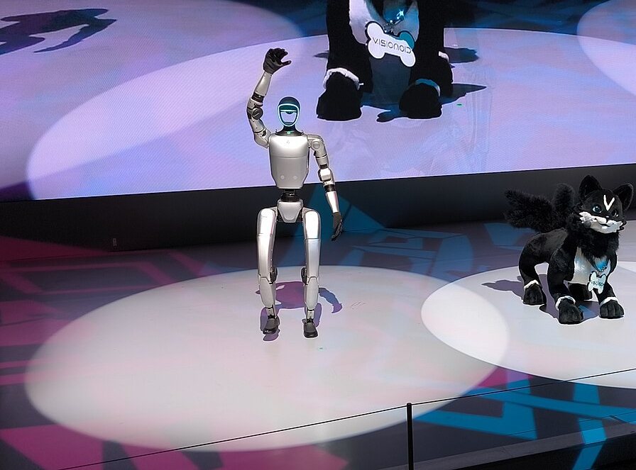 A compact humanoid robot waving on an exhibition stage